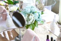 a spa bridal shower setting with pastel blooms, glass bowls, mirrors, nail polishes and potted orchids and candles