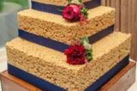 a square krispie rice wedding cake with navy ribbons and bold red blooms and greenery is a timeless option
