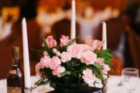 a stack of books, a black vase with pink flowers and candles around to compose a beautiful vintage wedding centerpiece