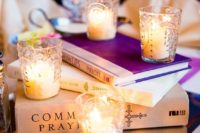 a stack of books on a mirror tray with candles in glass candle holders is a laconic and very budget-friendly idea