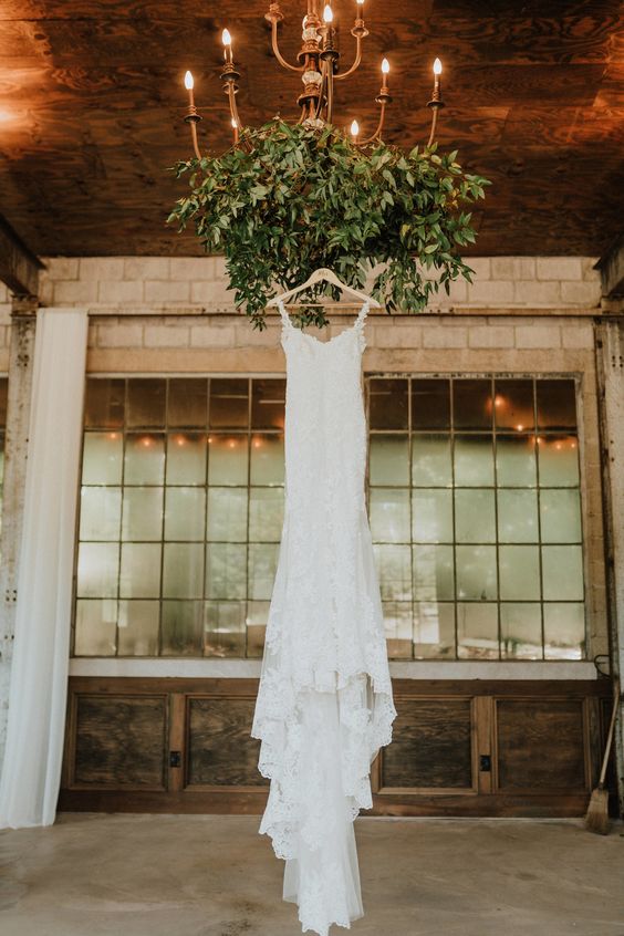 a vintage oversized wedding chandelier decorated with lush textural greenery for a natural feel is a lovely wedding decor idea
