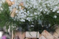 a wedding centerpiece of a large jar with wine corks, baby’s breath, greenery and twigs for a vineyard wedding