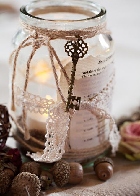 a wedding decorations of a jar with a candle, lace, twine, a vintage key and some acorns on the table is a great idea to rock
