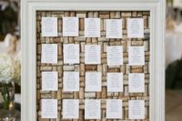 a wedding seating chart with wine corks and paper in a large frame is a stylish and chic idea