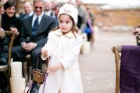 a white coat, a white beanie, shiny flats and a neutral dress for a comfortable winter flower girl look