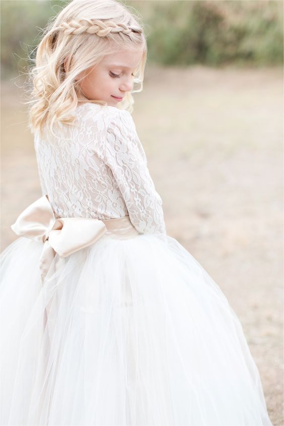 a white lace long sleeve top, a white tulle skirt, a silk bow for a chic and beautiful winter flower girl look