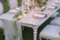 a white tulle table runner with a greenery and yellow bloom one create a chic and beautiful tablescape
