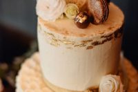 a white wedding cake with a plain and a textural tier, white blooms, macarons and some gilded acorns is a beautiful solution for a fall wedding