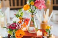 books, candles and mini vases with just some blooms in bold colors make up a cool, fresh and bold wedding centerpiece