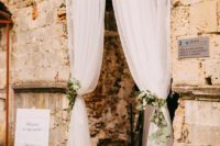 elegant white tulle curtains with fresh eucalyptus can decorate the entry to a reception or ceremony space