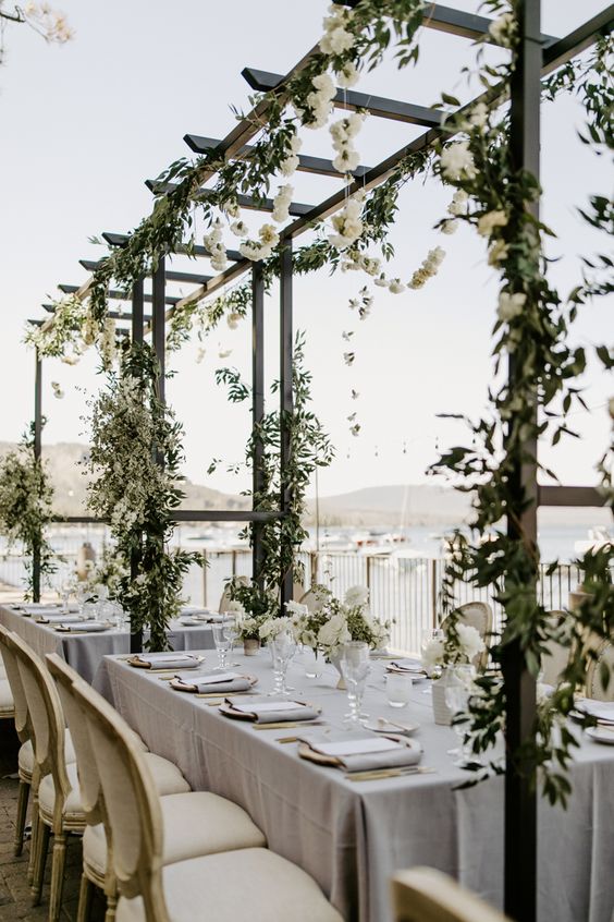 frames and ladders over the tables covered with greenery and white blooms make the wedding reception space feel fresh