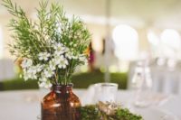 moss covered books, an amber glass vase plus wildflowers and greenery is a simple and rustic idea