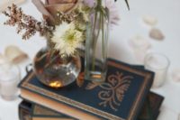 navy books, two clear vases with simple blooms and a single dusty pink rose for a beautiful look
