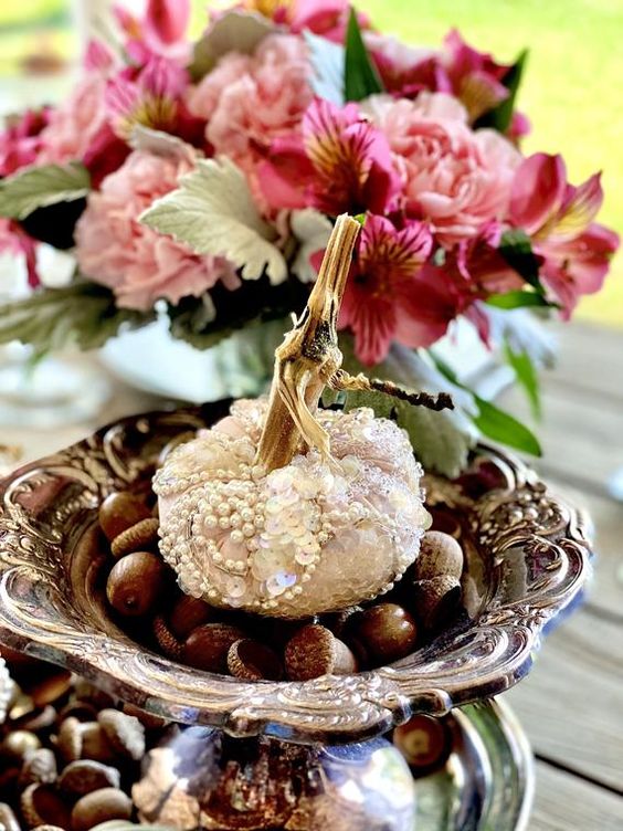 refined fall wedding decor of tiered plates with acorns and a pearled and sequined pumpkin on top is stylish and chic