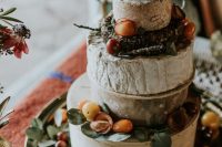 a beautiful rustic cheese wheel cake tower topped with herbs and tomatoes is a lovely idea for a rustic wedding