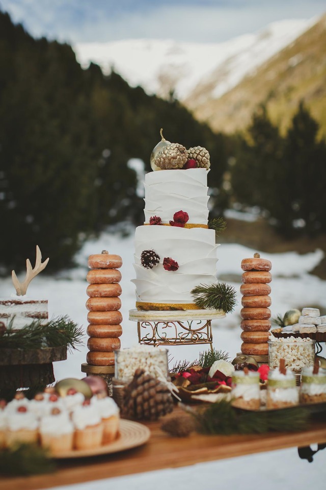 a boho rustic winter wedding cake with tiers of chocolate, gilded pinecones and pears, blooms and berries
