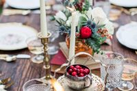 a boho tablescape with copper and gold accessories, crystal glasses, cranberries, thistles and eucalyptus and candles