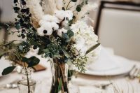 a boho winter wedding centerpiece of air plants, dried flowers, white blooms, cotton and grasses plus candles