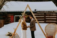 a boho winter wedding space with boho rugs, faux fur, an arch decorated with dried blooms and leaves, candle lanterns