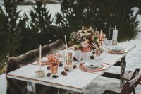 a boho winter wedding tablescape with candles, copper chargers and candleholders, neutral wintry blooms and pale greenery