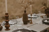a boho winter wedding tablescape with pritned napkins, porcelain plates and vases, wooden candleholders