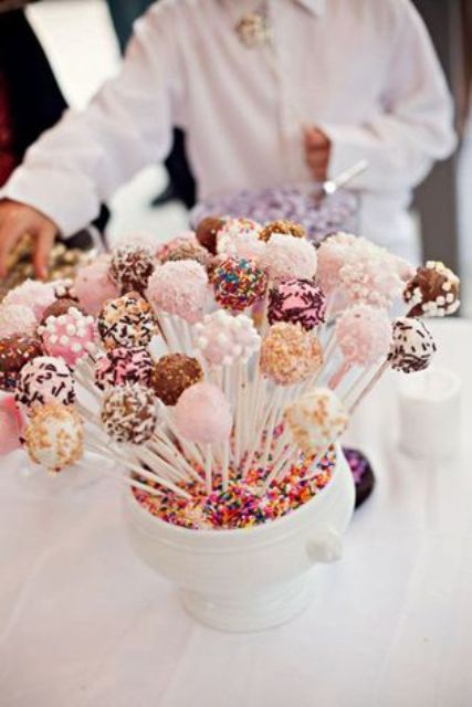 a bowl filled with confetti and lots of delicious and fantastic cake pops for a bright modern wedding
