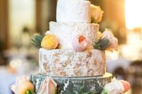 a cheese wheel wedding cake topped with peachy and blush blooms plus thistles, for a rustic spring or summer wedding