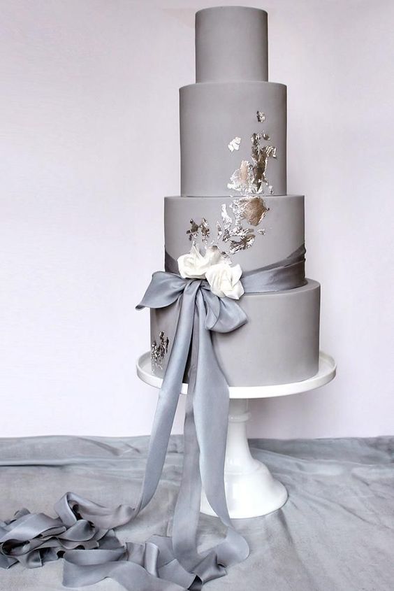 a chic plain grey wedding cake with silver leaf, a grey and white silk ribbon bow is a modern and stylish piece