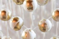 a clear acrylic stand with white and gold cake pops is a gorgeous idea for a modern glam wedding, they are very crowd-pleasing