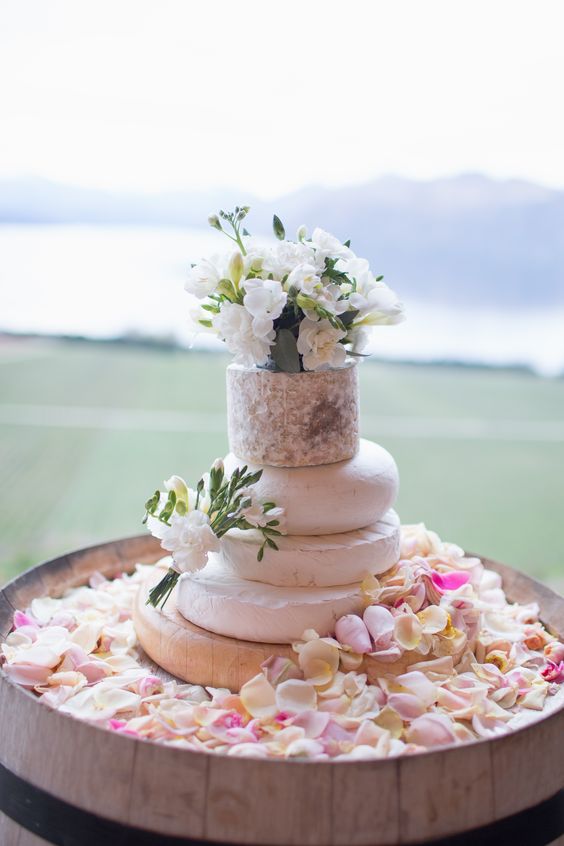 a delicate cheese wheel wedding cake topped with white blooms is a lovely idea for your delicate and neutral wedding