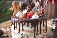 a gingerbread naked wedding cake topped with edible ornaments, chocolate and gingerbread cookies, meringues and other stuff plus chocolate drip