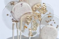 a grey marble wedding cake topped with clear and white lollipops decorated with gold is amazing