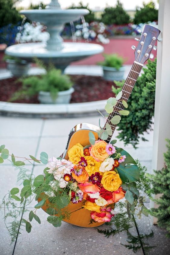 a guitar with bright blooms and greenery is a lovely idea for a beuatiful and romantic wedding