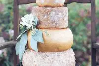 a huge cheese tower with greenery and flowers and some cherries for displaying is a lovely idea for a summer or fall wedding