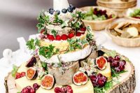 a messy cheese wheel and just cheese wedding tower with lots of fresh fruit and berries plus herbs is a gorgeous idea for a rustic wedding