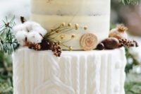 a naked and frosted wedding cake with a sweater pattern, cotton, berries, nuts, cookies and fir