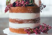 a naked wedding cake topped with berries, white and deep purple blooms and greenery will fit a fall or winter wedding