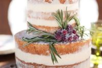 a naked wedding cake with evergreens and sugared cranberries for a rustic winter wedding