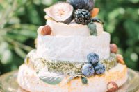 a pretty and small cheese wheel wedding cake topped with fresh berries and fruit, with greenery is a lovely idea for a fall wedding