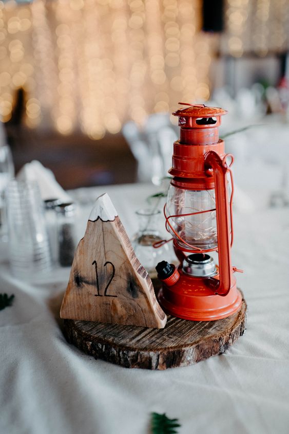a rustic and camp winter wedding centerpiece of a wood slice, a mountain of wood and a lantern is great