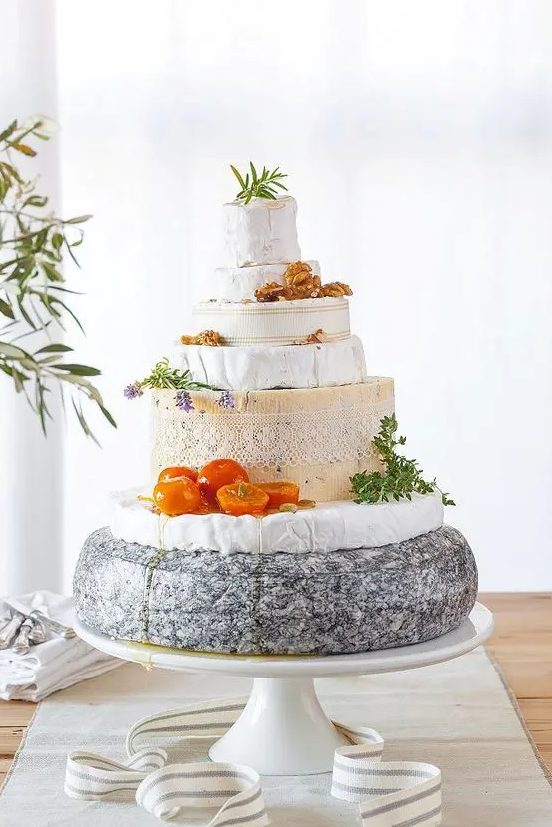 a rustic cheese tower on a stand, with tomatoes, herbs, nuts is a cool idea for many laid-back and relaxed weddings