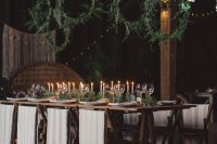 a rustic winter wedding venue with greenery and fern embroidery hoops, a greenery runner, candles, wood slices and tree stumps