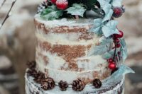 a semi-naked wedding cake with a vanilla and chocolate part, with leaves, pinecones and berries for a winter wedding