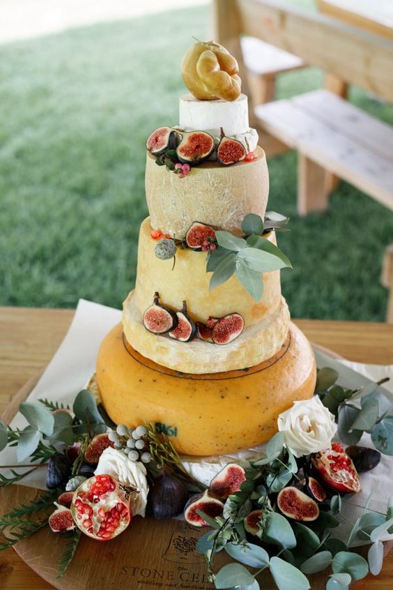 a tall cheese wheel wedding cake with figs and greenery plus berries on top is a gorgeous idea for a summer wedding