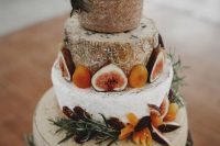 a tall rustic cheese wheel wedding cake topped with fresh fruit and berries plus herbs is a gorgeous idea to rock at the wedding