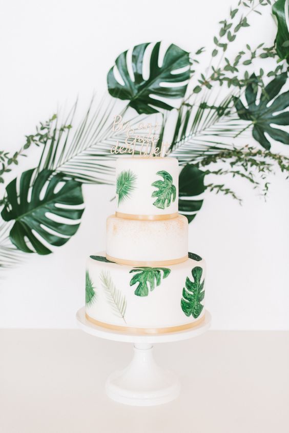 a tropical wedding cake with painted grene leaves and gold ribbons is a fresh and modern option for a modern tropical wedding