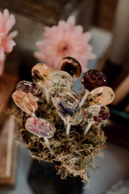 a vase with moss and clear lollipops with edible flowers is amazing for your wedding dessert table, they are very affordable