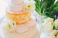 a vintage white cake stand with cheese wheels and white blooms for decor is ideal for a delicate and chic weddign with a vintage feel