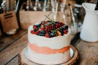 a white and peachy buttercream wedding cake topped with fresh berries and greenery is a lovely wedding dessert