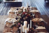a winter boho lux wedding tablescape with candles, greenery and bold blooms, gold cultery and gold rimmer plates